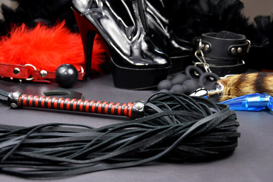 Leather flogger whip sex toys on a dark background stock photo images. Set of erotic toys for BDSM stock photo. Adult sex toy, flogger, ball gag, handcuffs, anal plug and high heel shoes images