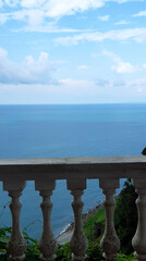 View on the Black sea from high hill in garden. Old railings, plants, sky and clouds. Nature.