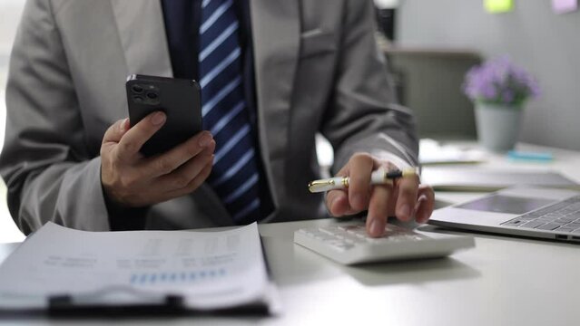 Businessman is checking invoices online by mobile phone and calculating income and expenses and planning finances.