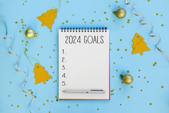 New Year goals List 2024 with notebook written in handwriting about plan listing of new year goals, expectations and resolutions setting. flat lay style. Christmas planning concept.