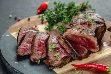 Sliced medium rare grilled steak on a wooden board, top view. copy space