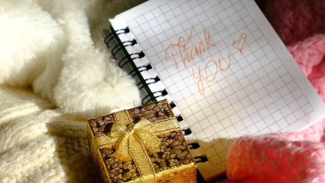 A golden gift box and sniny  golden sparkles bokeh.  Text Thank You on paper, notepad. Wedding, Birthday, Valentines Day,  dating. 