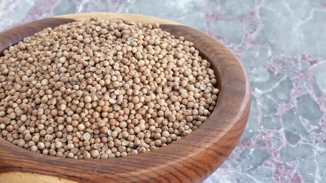 coriander seeds on brown wooden plate on blue marble,pan, close, HD, 24fps