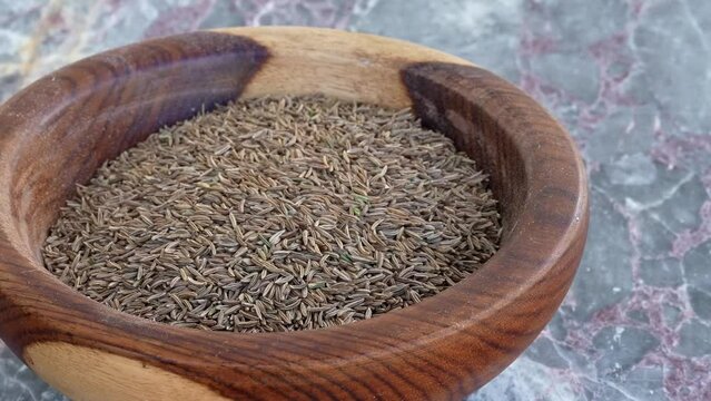 cumin seedsin brown wooden plate on blue marble ,pan, close, HD, 24fps
