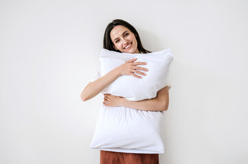 Portrait of joyful smiling woman in stylish pajama hugging pillow