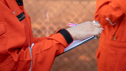 Action of safety officer is writing and check on checklist document during safety audit and inspection at drilling site operation. Industrial expertise occupation working scene.