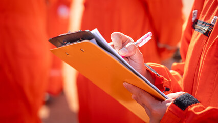 Action of safety officer is writing and check on checklist document during safety audit and inspection at drilling site operation. Industrial expertise occupation working scene.