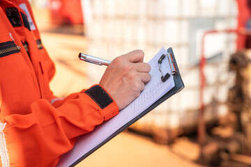 Action of safety officer is writing and check on checklist document during safety audit and...