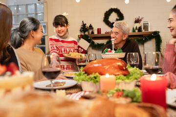 Happy Asia girl holding food with family celebrating Christmas in dinner at home