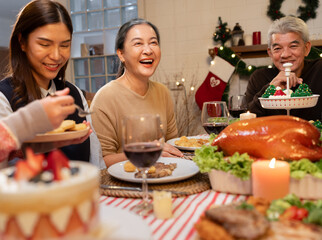 Asian family gathering at home having dinner celebrating Christmas and Grandmother is happy to...