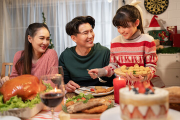 Happy Asian family mother, father and daughter having dinner celebrating Christmas at home	