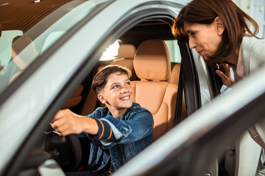 Little boy testing new car with mother at dealership