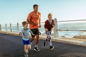 Father jogging with his kids by the ocean