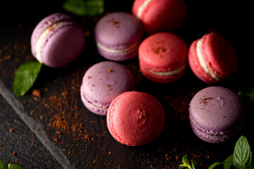 Colored macaroons. Delicious sweet colorful French desserts on black background