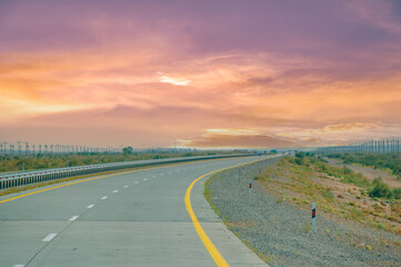 Beautiful prairie landscape with a concrete road leading into the distance. Stunning sunset colors...