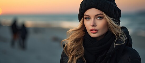 The young and beautiful woman stood on the beach, surrounded by people enjoying the winter nature. With a happy and carefree expression, the girl showcased her fashion-forward style, wearing a