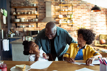 Happy father helping his children with homework at home