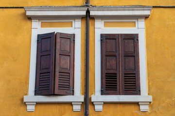 Persiane in legno sulla facciata gialla della vecchia casa, Palmanova, Italia.