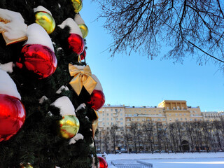 Christmas tree decorated with red and golden baubles on a sunny day in Moscow, Russia. City...