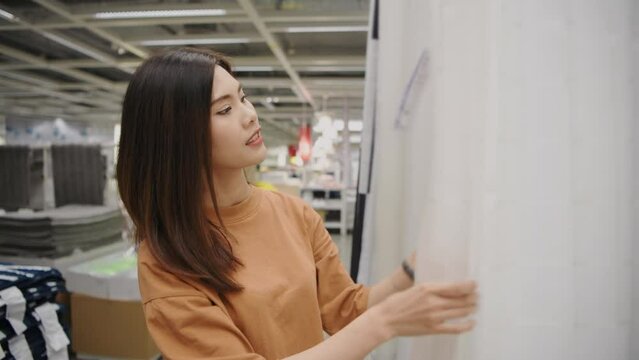 Shopping concept of 4k Resolution. Asian woman shopping for curtains in a department store.