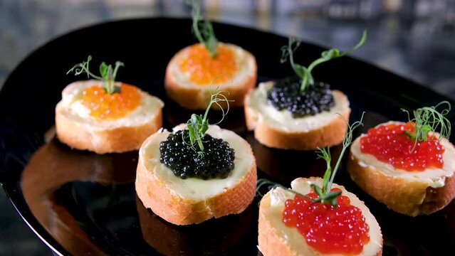 three types of caviar black and red served appetizer high cost on swirling black plates close-up