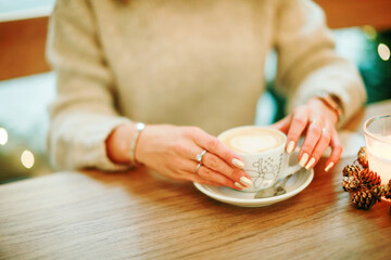 Top view of female hands keeping cup of beverage in cafe. Coffee break concept.