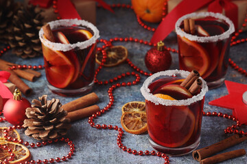 Three glasses with mulled wine with fruits and cinnamon sticks