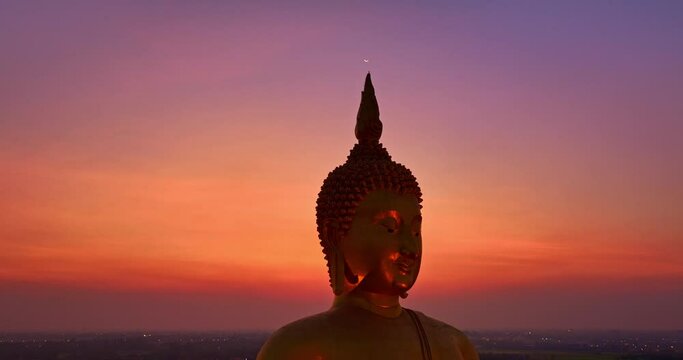 .aerial view The moon was above the head of the biggest golden Buddha in the world at twilight. .low night atmosphere golden big buddha was popular landmark and famous at wat Muang Ang Thong Thailand