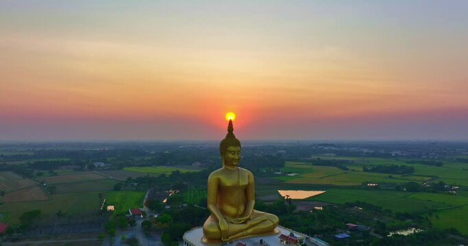 .aerial view The sun was above the head of the biggest golden Buddha at sunset..landmark of Buddhism in Thailand..video 4K Nature video High quality footage for worship and travel concept..