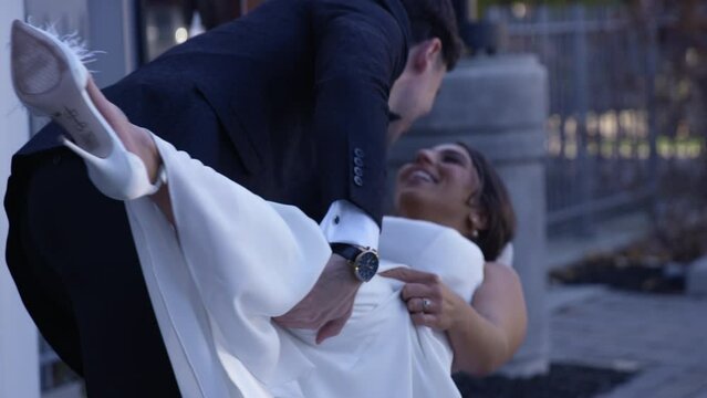 Groom dipping newly wed bride for kiss outdoors - slow motion