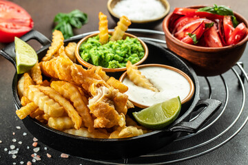 Authentic traditional British cuisine fish and chips served with mashed peas, vegetable salad,...