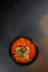 Traditional red soup bulgur, tomatoes and ribs in bowl. vertical image. top view. copy space for text
