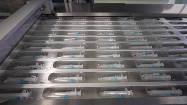 Medical syringe production plant. New syringes with needle on conveyor line. Equipment for the production of disposable syringes.
