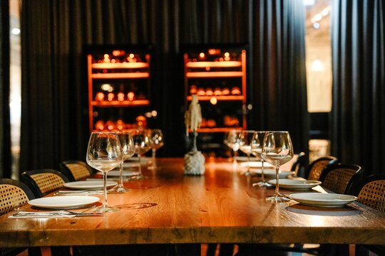 long bar table with line of chairs and wine glasses next to each chair with warm light vibe