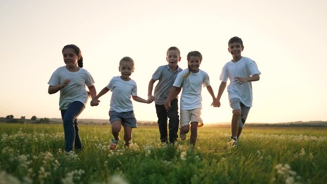 happy family. team of child run on green grass in summer at sunset in park. Child play outdoors in summer. group of child run and play on green meadow.Fun freedom summer vacation.Happy family concept