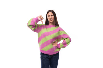 well-groomed slim young european brunette woman dressed in a striped pink-green pullover on a studio background