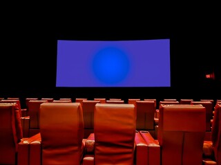 Blue glowing widescreen on a black wall in a theatre with empty orange leather seats
