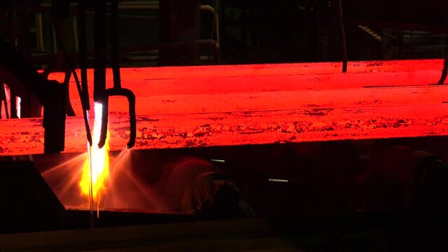 Iron foundry. Continuous casting machine. Production of steel billets. Continuous casting machine with blow torch working.  hot steel on conveyor in steel mill. Steel Billets at Torch Cutting
