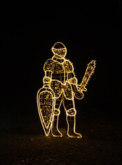 Warrior with sword and shield decoration made from small lights on black background