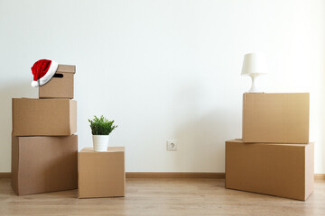 Santa Claus hat on cardboard boxes for moving at room. Movement before christmas