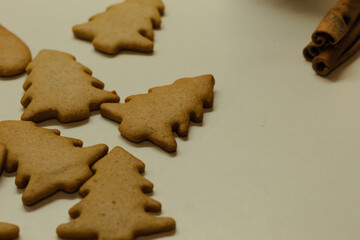 Many different gingerbread with cinnamon. New Year's brown cookies on a white background. Homemade baked goods for the festive table. Background of chaotically arranged gingerbread cookies.