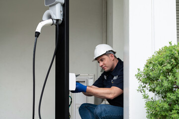 Qualified technician install home EV charging station, providing maintenance service for electric...