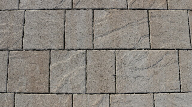 graphic resource of a fragment of a pavement or wall lined with gray stone tiles, a textured surface of a light hard material with wavy lines in the pattern