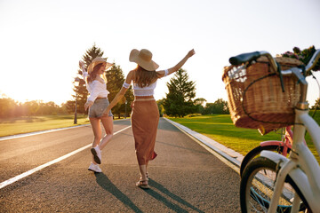 Young female friends enjoying road trip on bicycle spending weekend together
