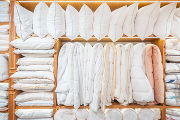 A lot of white bed linen on display in a store on wooden shelves