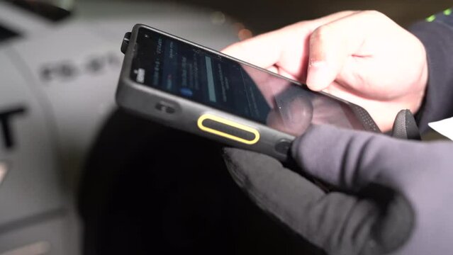 A security guard is conducting a circle check on his patrol fleet vehicle car with a digital report system on his phone.