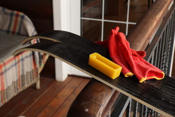 A block of yellow paraffin wax and red gloves on the black sliding surface of skis