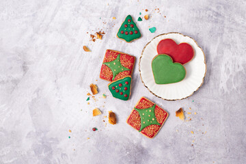 Handmade butter cookies with Christmas decoration in red and green tones on a plate and marble surface