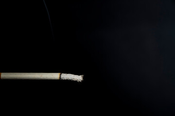 Smoking, burnt cigarette. Harm to health. Dark background, ash.