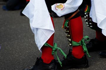 dancing feet in black shoes and clogs and red stockings on a tarmac pavement